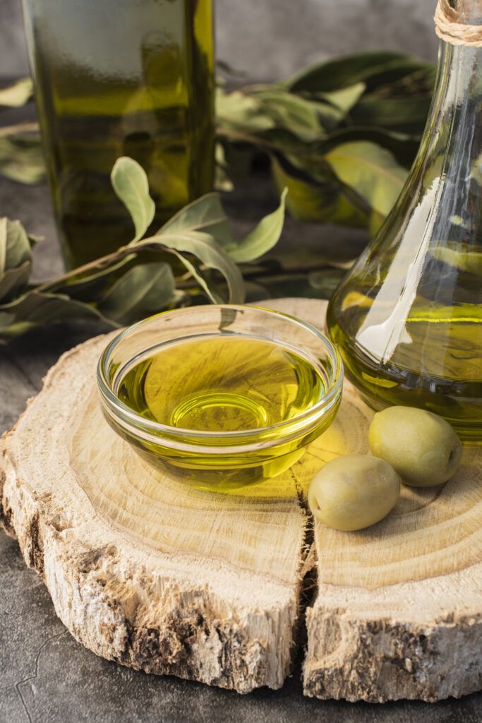 aceite de oliva virgen extra dorado cayendo de una cuchara de madera, con aceitunas frescas de fondo